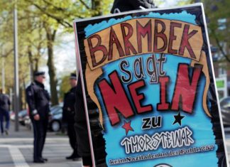 Der Laden, den hier keiner will Aktivist mit Mahnwachen-Plakat.