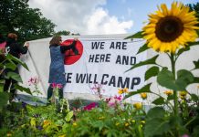 Die Odyssee der Camper Unterstützer des G20-Protestcamps befestigen Banner im Eingang des Stadtparks. Foto: Christina Sabrowsky/dpa