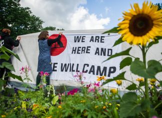 Die Odyssee der Camper Unterstützer des G20-Protestcamps befestigen Banner im Eingang des Stadtparks. Foto: Christina Sabrowsky/dpa