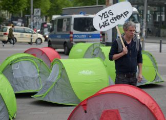 “Hecken schützen statt Heckenschützen!” Ein G20-Gegner läuft am 13.05.2017 in Hamburg auf dem Karolinenplatz mit einem Schild mit der Aufschrift «Yes we camp» an Zelten entlang. Der Bezirk Hamburg Nord kann das geplante Camp der Gegner des G20-Gipfels im Stadtpark nicht verbieten.