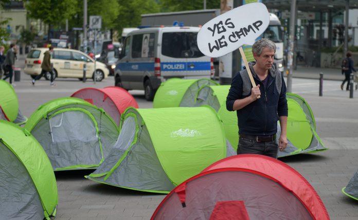 Ein G20-Gegner läuft am 13.05.2017 in Hamburg auf dem Karolinenplatz mit einem Schild mit der Aufschrift «Yes we camp» an Zelten entlang. Der Bezirk Hamburg Nord kann das geplante Camp der Gegner des G20-Gipfels im Stadtpark nicht verbieten.