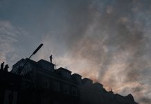 Zerstörte Scheiben, brennende Autos: Wer zahlt? Autonome auf dem Dach eines Wohnhauses am Schulterblatt.