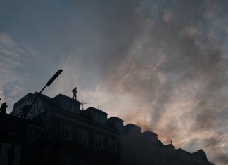 Zerstörte Scheiben, brennende Autos: Wer zahlt? Autonome auf dem Dach eines Wohnhauses am Schulterblatt.