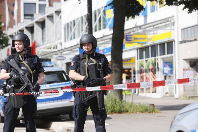 Einsatzkräfte der Polizei sperren am 28.07.2017 nach einer Messerattacke in einem Supermarkt in Hamburg den Tatort ab. Foto: Paul Weidenbaum/dpa