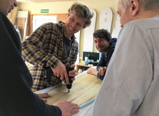 Fräsen, schleifen, lossurfen – Selfmade-Kiteboards aus Eidelstedt Jannek Grocholl lachend, mit Teilnehmern über dem Kiteboard
