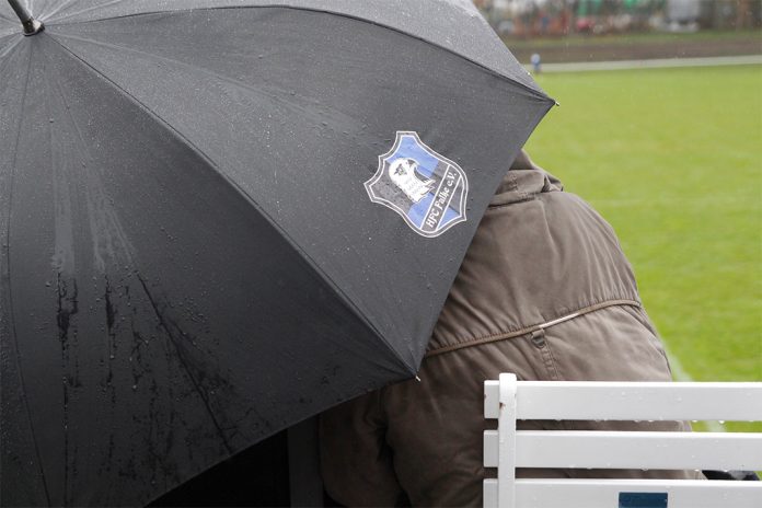 Ein Regenschirm des HFC Falke schützt Fans vor dem Regen.