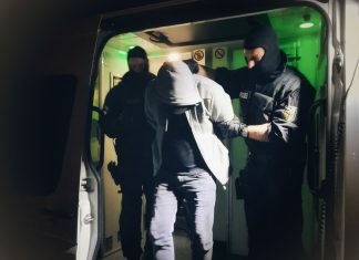 Polizisten führen einen Verdächtigen ab, der im Rahmen einer Razzia vorläufig festgenommen wurde