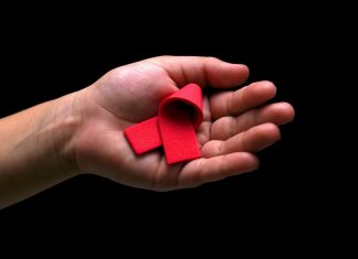 Anzahl der HIV-Infizierten weiter gesunken Hand mit roter HIV/AIDS-Schleife