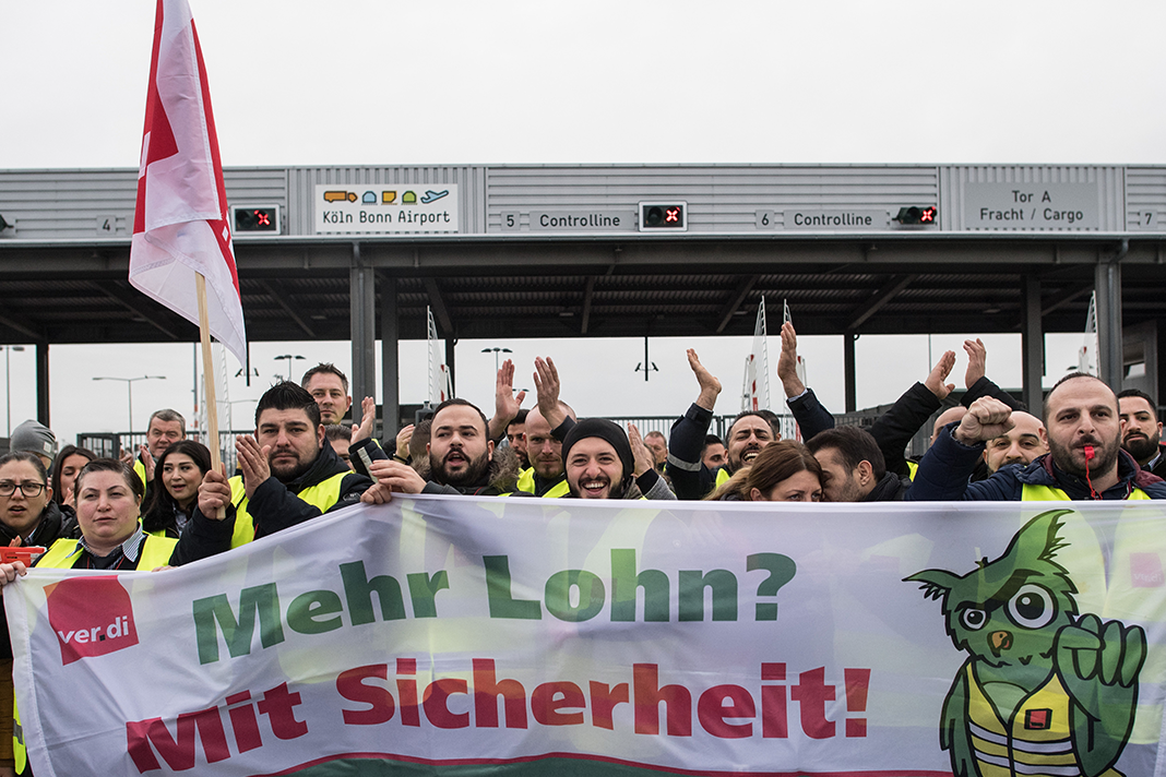 Mitglieder der Gewerkschaft Verdi stehen mit Fahnen vor dem Flughafen. An den Airports Köln/Bonn, Düsseldorf und Stuttgart findet ein ganztägiger Warnstreik des Sicherheitspersonals statt. Foto: Federico Gambarini/dpa