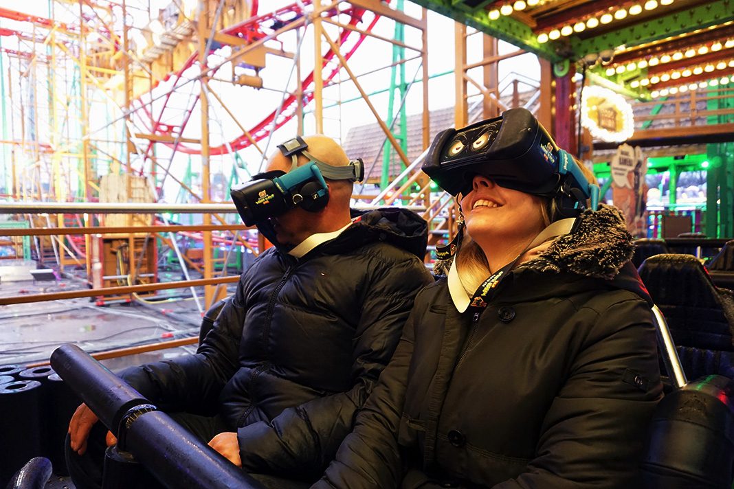 Ein Mann und eine Frau sitzen in einem Wagen der VR-Achterbahn Wilde Maus XXL.