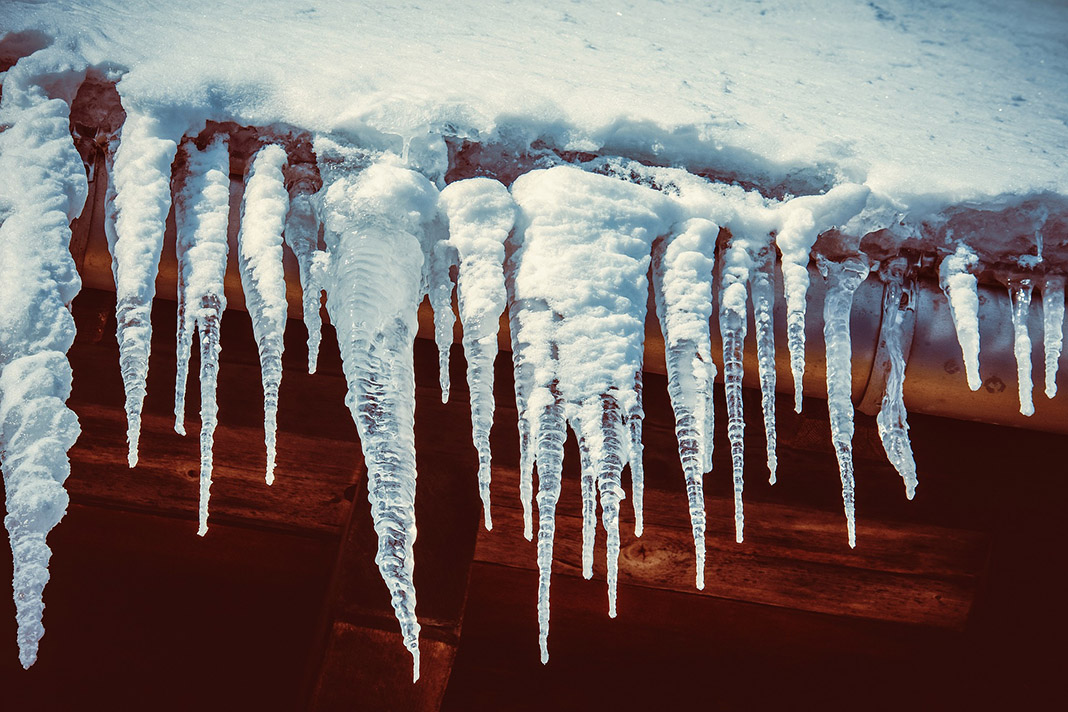 Eiszapfen haengen an einem Dach.