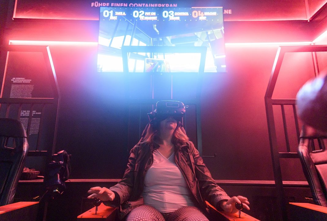 Eine Besucherin der Discovery Docks steuert bei der Eröffnung der Hafen-Erlebniswelt mit Hilfe einer VR Brille virtuell einen Containerbrückenkran.