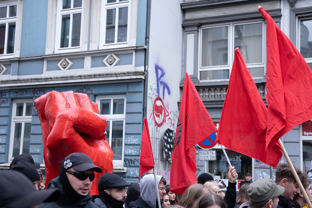 Menschen tragen einzelne Buchstabenplakate durch Hamburgs Straßen, die das Wort "Enteignen" bilden.