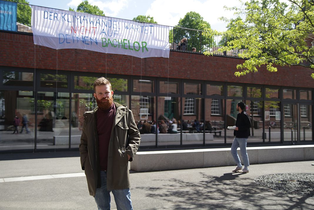 Laurenz Rau vor dem Banner auf dem HAW Campus Finkenau