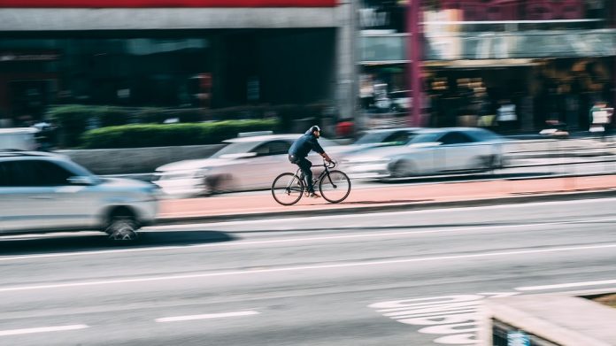 Ein Fahrradfahrer fährt auf einem Radweg zwischen zwei Straßen