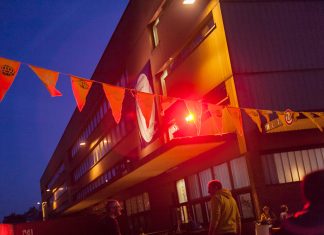 Kurzfilm Festival: Lange Woche der kurzen Filme Ein Gebäude im Hintergrund. Davor einen Fahnengirlande in rotem Licht.