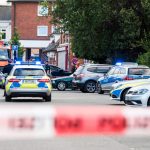 Tödliche Schüsse in Lohbrügge Polizisten und Feuerwehrleute stehen am Tatort in Lohbrügge. Vorne ist ein Absperrband zu sehen.