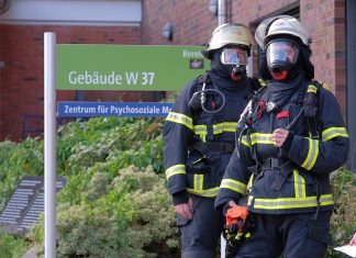 Vier Verletzte bei Brand im UKE Zwei Feuerwehrleute stehen vor dem UKE in Hamburg.