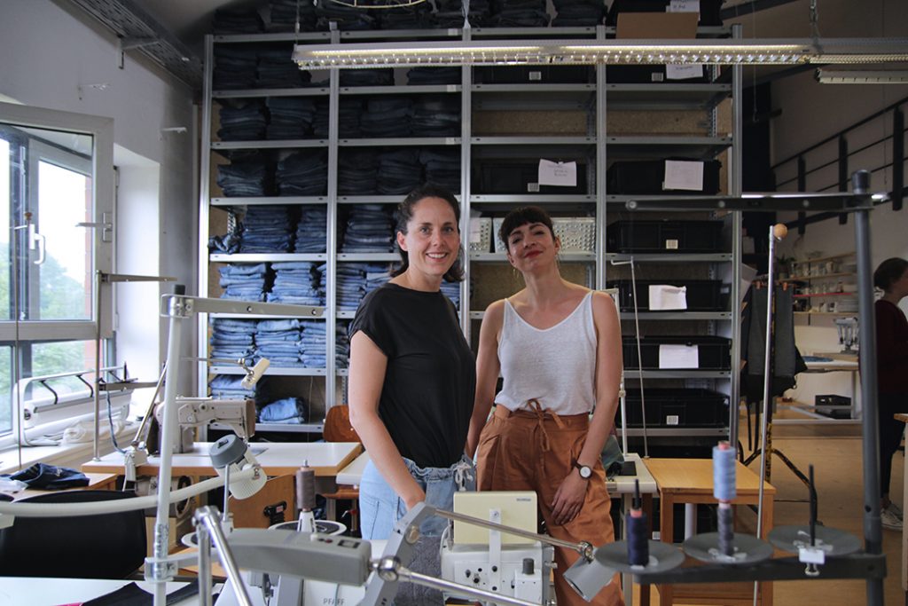 Gründerinnen Lotte (links) und Conny (rechts) vor dem großen Jeansregal in der Werkstatt