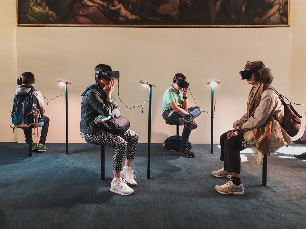 Menschen sitzen auf Stühlen und tragen VR-Brillen.