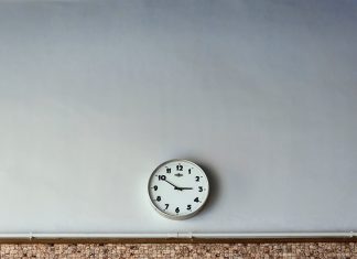 Kein Lohn für zu viel Arbeit Große graue Wand mit einer analogen Uhr