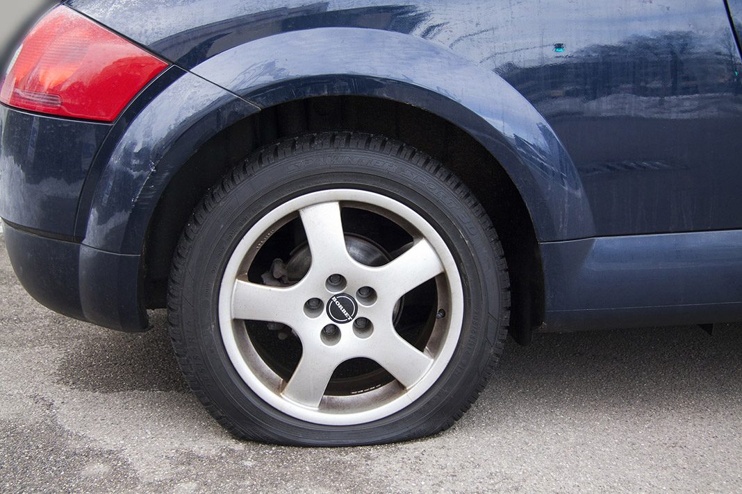 Ein beschädigter Reifen an einem blauen Wagen.