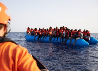 Seenotrettung: Hamburg will Geflüchtete aufnehmen Mittelmeer: Die von der Seenotrettungsorganisation Sea-Eye herausgegebene Aufnahme zeigt einen Seenotretter (l) der zu einem Flüchtlingsboot schaut. Nach dem Drama um das Rettungsschiff «Sea-Watch 3» hat nun eine andere deutsche Hilfsorganisation Migranten vor Libyen mit ihrem Schiff aufgenommen. Die «Alan Kurdi» habe 65 Menschen in internationalen Gewässern auf einem überladenem Schlauchboot vor Libyen entdeckt und gerettet, teilte die Regensburger Organisation Sea-Eye am Freitag mit.