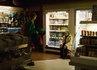 Eine Frau, eine Stadt, eine Nacht Frau sitzt in einem Supermarkt vor den Kühlschränken.