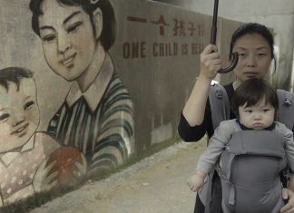 Ein Kind – so will es der Staat Nanfu Wang mit ihrem Kind vor einer Wand mit chinesischer Ein-Kind-Propaganda: "One Child is best"