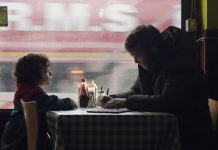 Audienz mit dem Gewissen Ausschnitt aus dem Film Bruno: Daniel und Izzy sitzen gemeinsam am Tisch