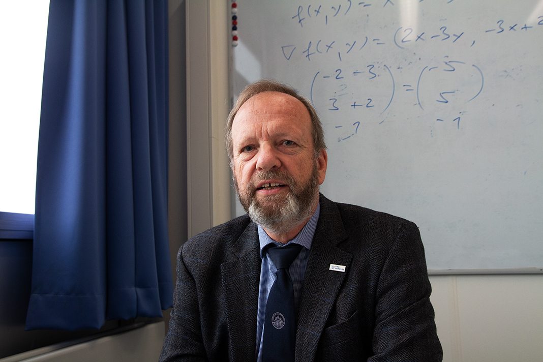 Portrait von Prof. Dr. Christoph Maas. Er sitzt in seinem Büro an einem Schreibtisch.