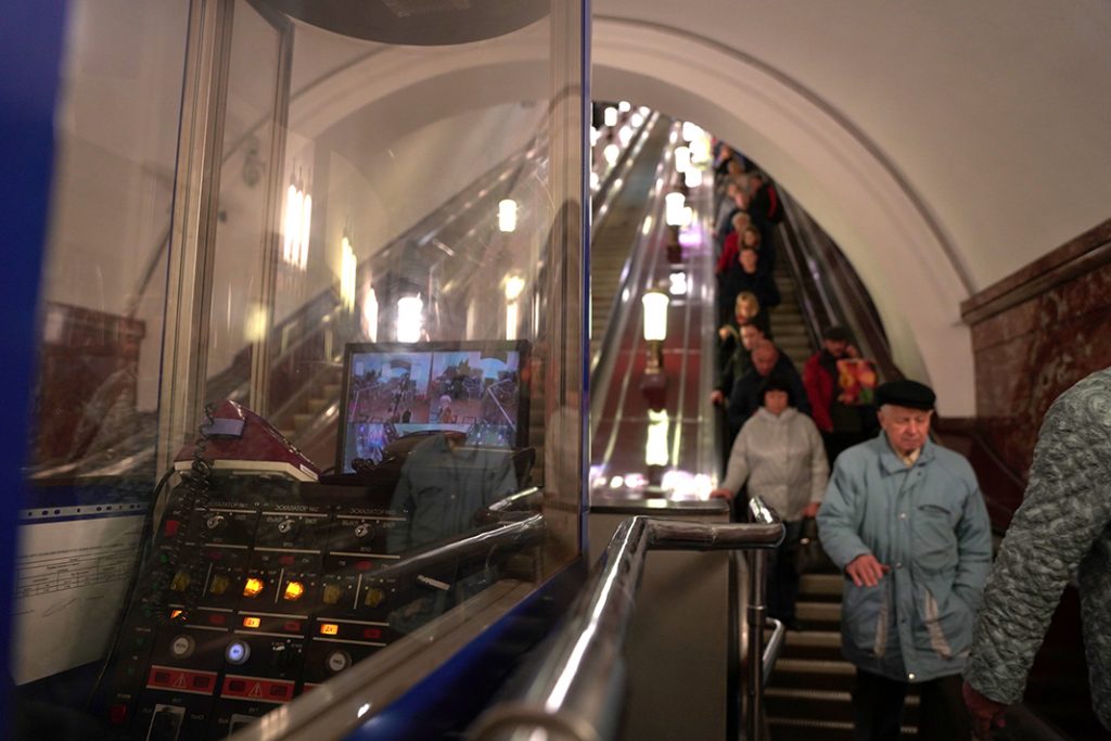 The escalator operators watch the people coming down to the subway.