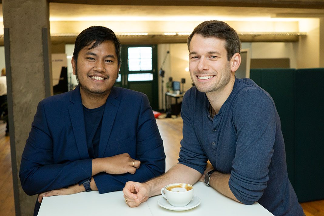 Zwei Männer stehen an einem Tisch. Sie haben ihr eigenes Start-Up für 3D-Sounds gegründet.