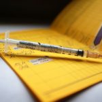 Hamburger Impfwoche gestartet Eine Spritze die mit dem Namen des Vierfach-Grippeimpfstoff Influvac Tetra gekennzeichnet ist, liegt auf einem Impfpass.