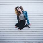 Glück ist in Hamburg jung und reich Eine Frau sprint hoch und zieht die Beine an.