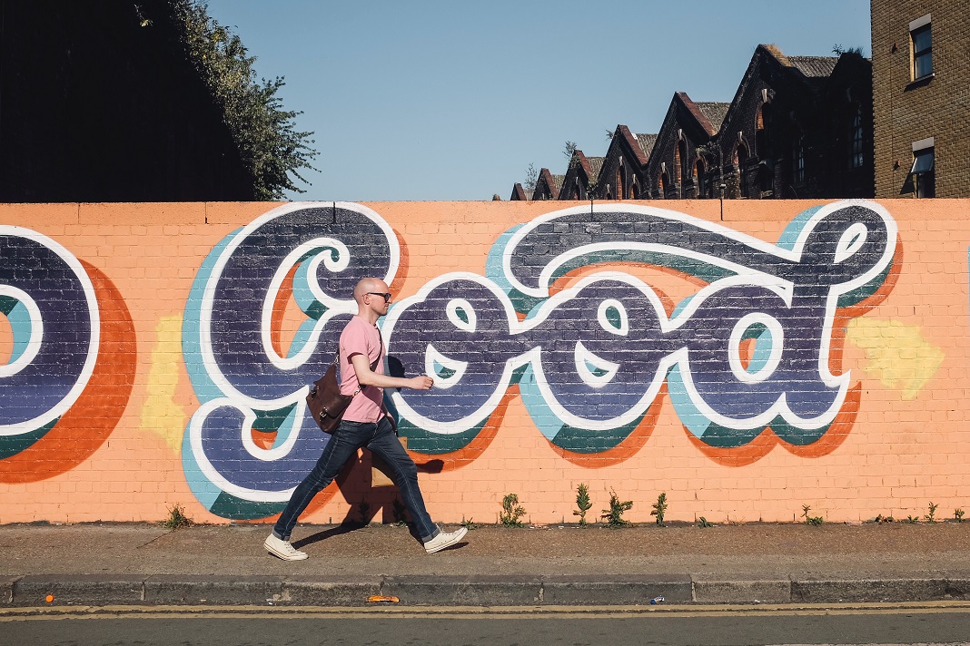 Ein Mann geht vor einer Wand mit Graffiti entlang.
