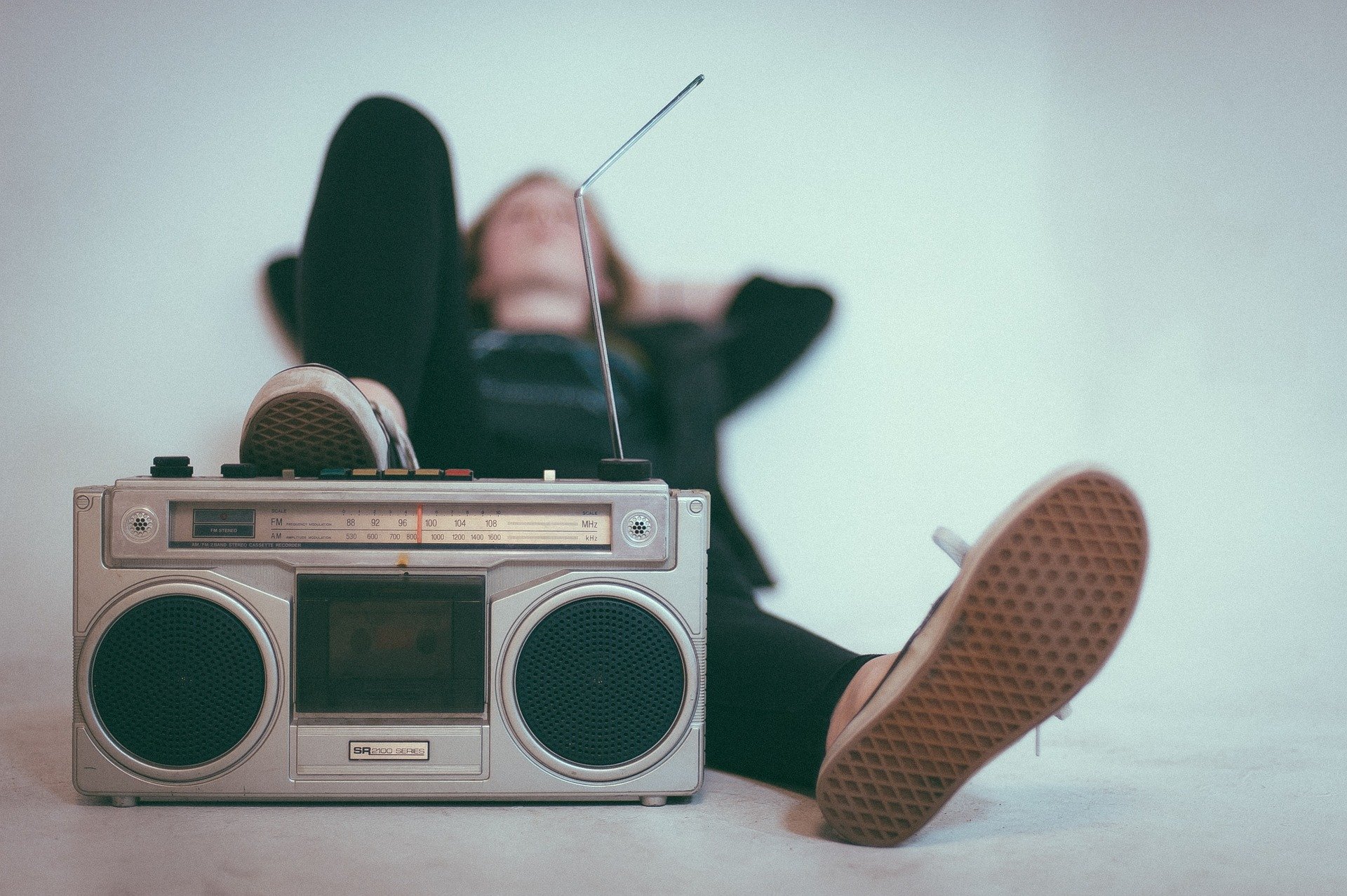 Ein Mann liegt auf dem Rücken und stellt seinen Fuß auf ein Radio mit Antenne