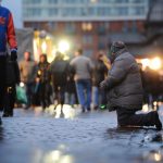 Fast jeder sechste Hamburger von Armut bedroht Ein Bettler kniet im Morgengrauen auf dem Fischmarkt am Hafen in Hamburg vor vorbeilaufenden Besuchern. Foto: Christian Charisius/dpa