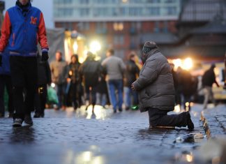 Fast jeder sechste Hamburger von Armut bedroht Ein Bettler kniet im Morgengrauen auf dem Fischmarkt am Hafen in Hamburg vor vorbeilaufenden Besuchern. Foto: Christian Charisius/dpa