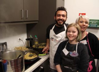 Appetit auf Neues: Zu Gast bei „Über den Tellerrand“ Drei Personen stehen vor einem Herd und schauen in die Kamera.