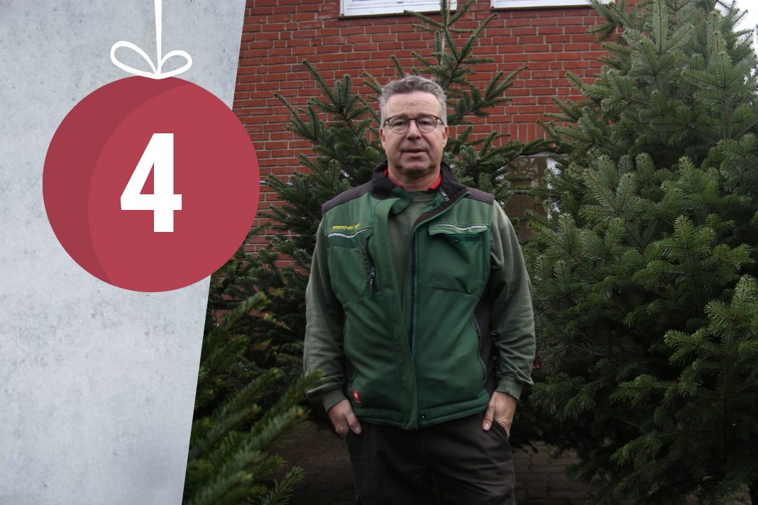 Kay Wortmann steht vor etwa zwei bis drei Meter hohen Weihnachtsbäumen in seinem Gartencenter.