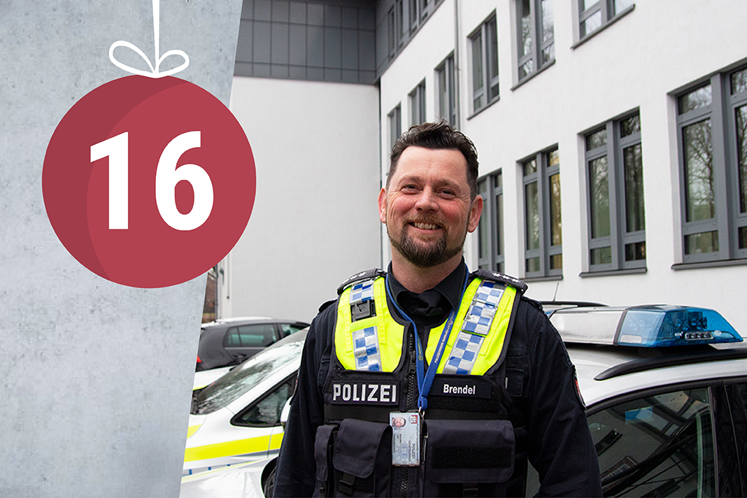 Polizist Olaf Brendel steht vor der Wache in Wilhelmsburg und lächelt.