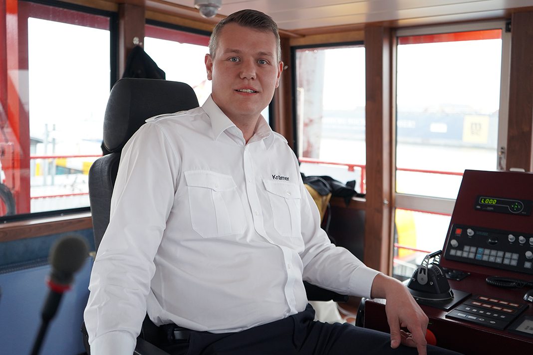 Alexander Krämer sits in the wheelhouse of a ferry in the port of Hamburg