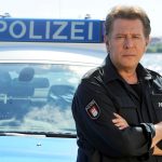 Hamburg in A(u)ktion: Versteigerung von Jan Fedders Küchenuhr Jan Fedder steht vor einem Polizeiwagen in Hamburg.