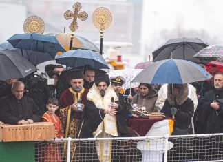 Orthodoxer Bischof segnet Elbe Grieschisch-orthodoxer Bischof segnet an Bord eines Schiffs das Wasser der Elbe, umringt von Menschen mit Regenschirmen.