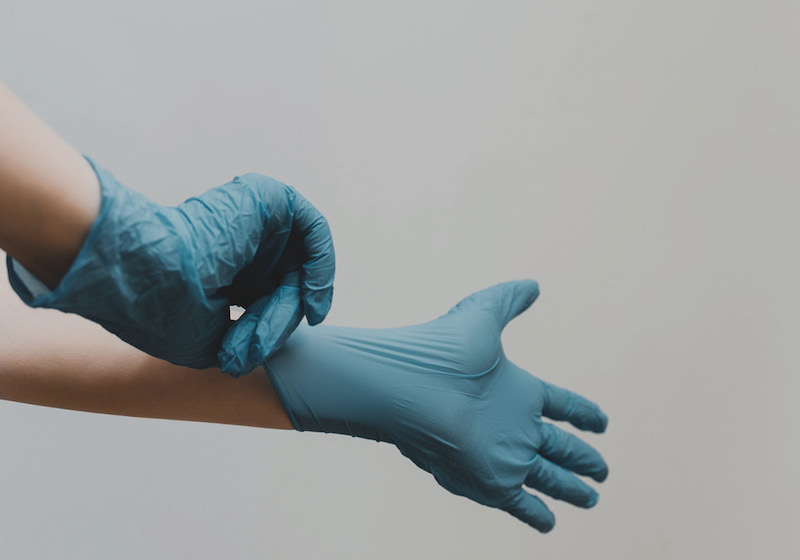 Zwei Hände in blauen Gummihandschuhen