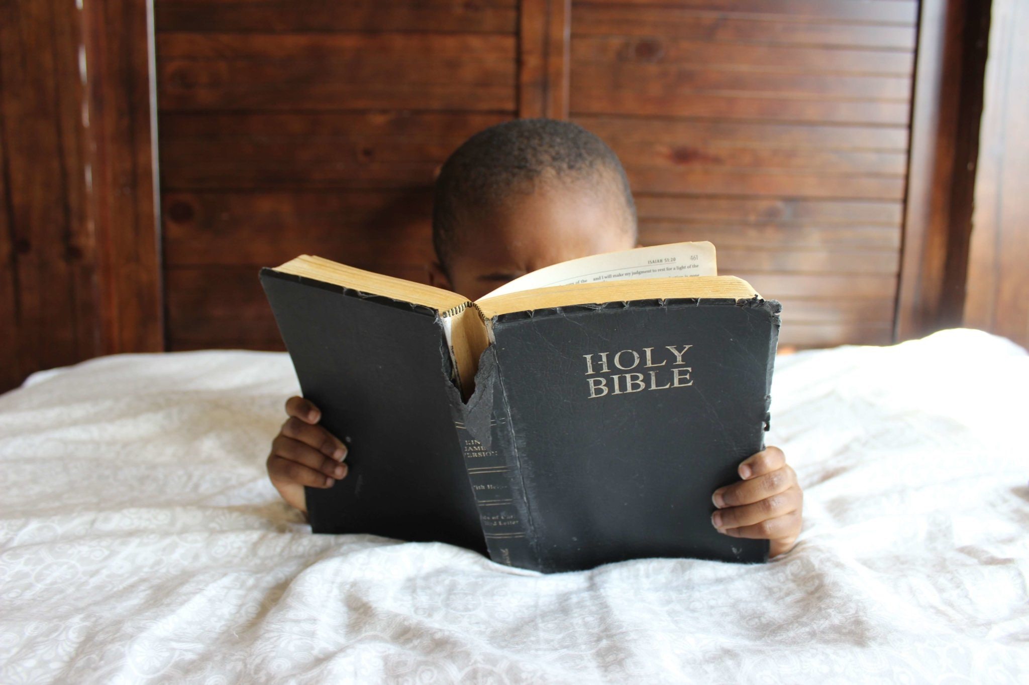 Junge im Bett mit Bibel