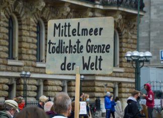 Demo vor dem Rathaus: “Leave No One Behind” Protestschild bei der "Seebrücke" Kundgebung