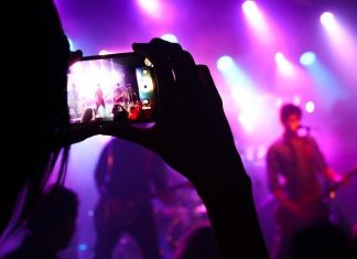 Hamburger Musiker*innen können Corona-Hilfe beantragen Person filmt Band mit Handy auf Konzert