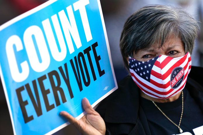 Eine Frau hält ein Schild mit dem Titel: Count every vote. Trumps Siegeserklärung erntet Kritik.